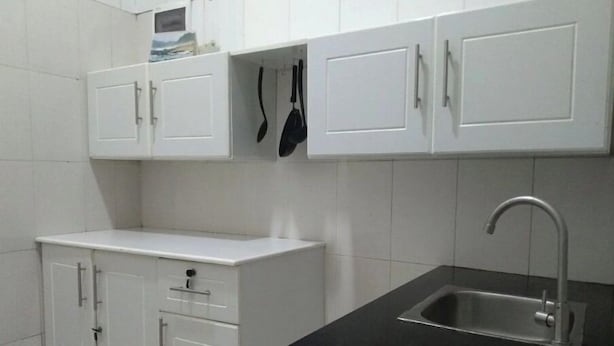 A kitchen with white cabinets, a black countertop, and a stainless steel sink. - Pretty Kigali studio. (Kigali)