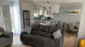 Een moderne woonkamer met een grijze bank, een geel poefje en een vloerkleed met een marmerpatroon.