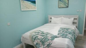 Een slaapkamer met een bed, een wit hoofdeinde en een lichtblauwe muur.