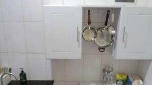 A small kitchen with white cabinets, a black countertop, a sink, and a black trash bin. - Kigali gorgeous Studio (Kigali)