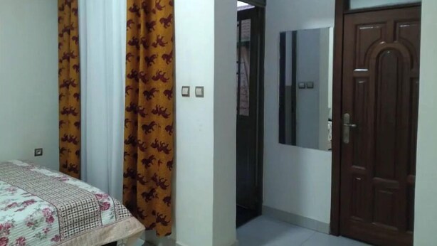 A bedroom with a bed, curtains, a door, and a mirror. - Kigali gorgeous Studio (Kigali)
