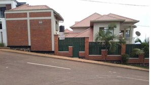 A two-story building with a brick facade and a green gate. - Kigali gorgeous Studio (Kigali)