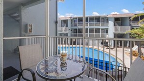 Ein Balkon mit Blick auf ein Schwimmbad und angrenzende Gebäude.