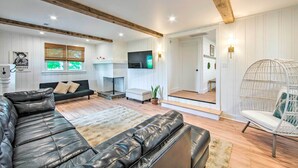 Un soggiorno moderno con un divano in pelle, una poltrona bianca e un trave in legno al soffitto.