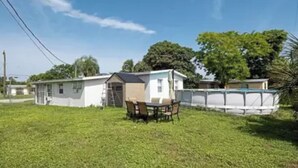 A mobile home with a small patio area, a table, and chairs. - Cozy little Home in Quiet neighborhood Off of major road (Port Charlotte)