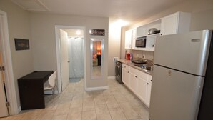 A compact kitchen with white cabinets, a stainless steel refrigerator, and a microwave. There's a small dining area with a table and chair. - 9min to the airport washer & dryer, kitchen, outdoor BBQ. Sleeps 4 (Las Vegas)