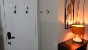 A hallway with a white door, a small table with a lamp, and a wall-mounted artwork. - 9min to the airport washer & dryer, kitchen, outdoor BBQ. Sleeps 4 (Las Vegas)