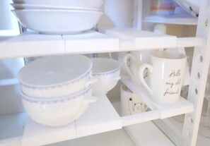A white shelf with bowls and a mug.
