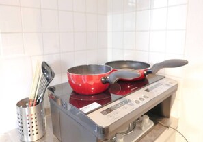 A kitchen with a stove, pots, and utensils.