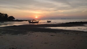 A beach with boats and a sunset.