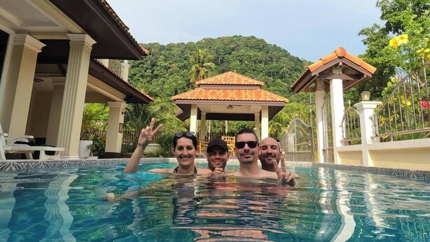 A swimming pool with a gazebo in the background, surrounded by lush greenery.