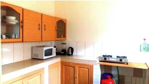 Cucina con mobili in legno, un forno a microonde, un bollitore e un piano cottura a gas.