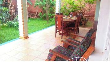 Relax in a serene outdoor seating area surrounded by lush greenery and a brick wall.