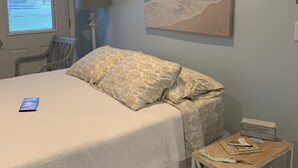 A bedroom with a bed, a lamp, a painting, and a small table with items on it. - Salt and Light Retreat for Overnight Stays in Rural South Dakota (Hayti)
