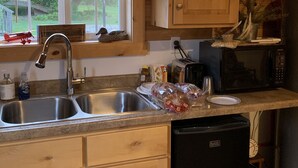 A kitchen with wooden cabinets, a stainless steel sink, a microwave, and a dishwasher. - Salt and Light Retreat for Overnight Stays in Rural South Dakota (Hayti)