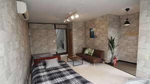 Una habitació moderna amb un llit, un sofà, una taula petita i una planta.
