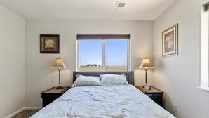 Una camera da letto con un letto grande, due comodini con lampade, una finestra con vista e quadri appesi alle pareti.