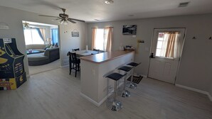 Una cucina moderna con isola centrale, sgabelli da bar e ventola a soffitto.