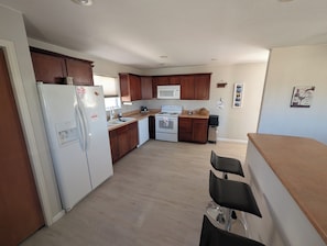 Une cuisine moderne avec des meubles en bois, un réfrigérateur blanc, un four à micro-ondes et une cuisinière.