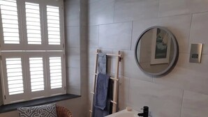 A bathroom with a white sink, a mirror, and a window with blinds. - Grade 2 Listed Georgian Townhouse by the sea (Penzance)