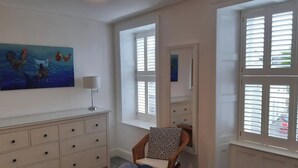 A bedroom with a bed, a dresser, a chair, and a window with blinds. - Grade 2 Listed Georgian Townhouse by the sea (Penzance)