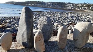 A rocky beach with large stones and a coastal town in the background. - Grade 2 Listed Georgian Townhouse by the sea (Penzance)