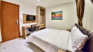 Una habitación de hotel con cama, escritorio, silla, televisor y un cuadro en la pared.
