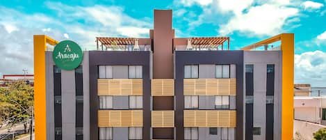 Un hotel moderno con un atrio central, balcones y un letrero llamativo que dice 'Aracaju Hotel'.