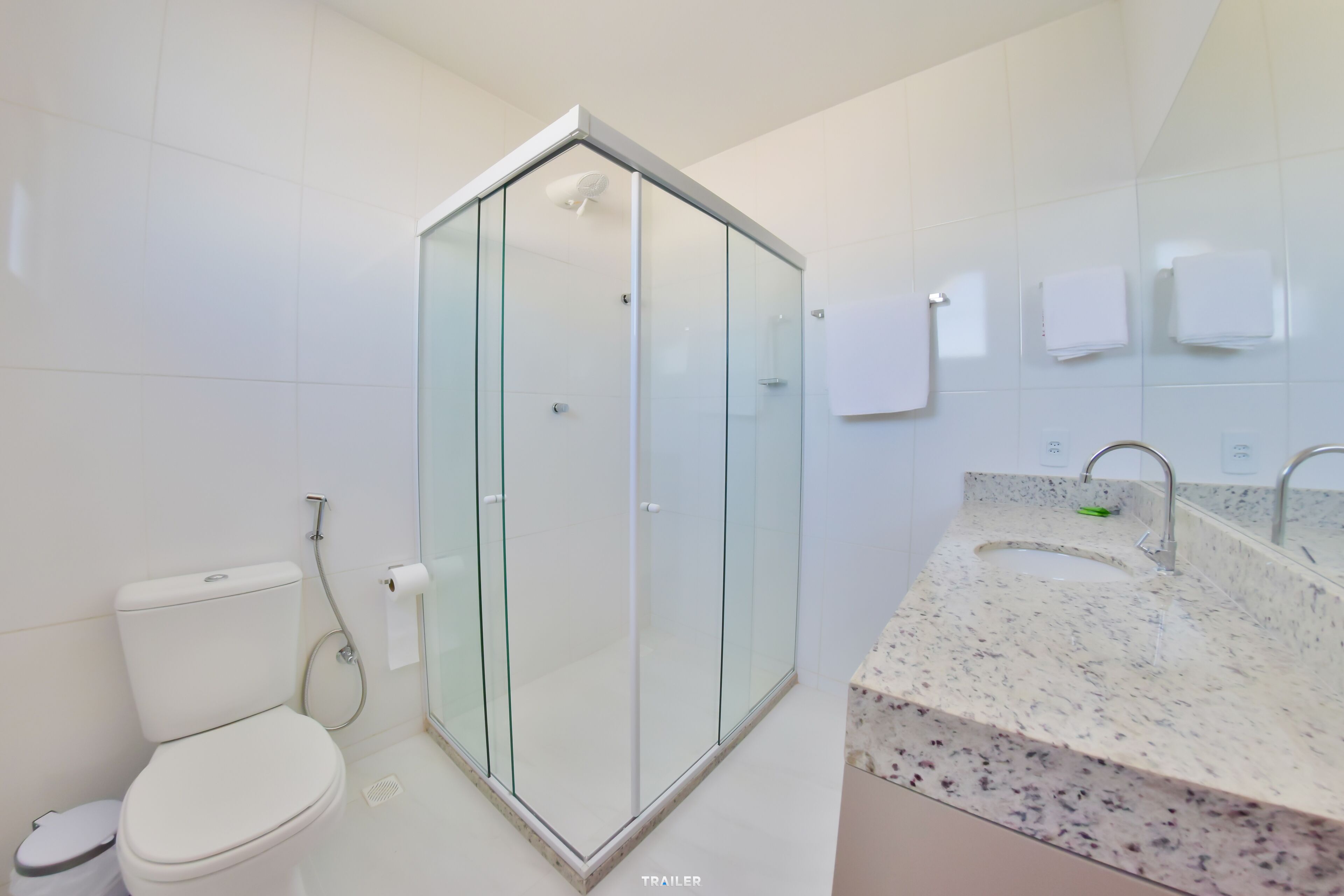 A modern bathroom with a glass-enclosed shower, a white toilet, and a marble sink with a mirror.