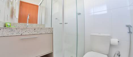 A modern bathroom with a glass shower enclosure, a toilet, and a sink with a marble countertop.
