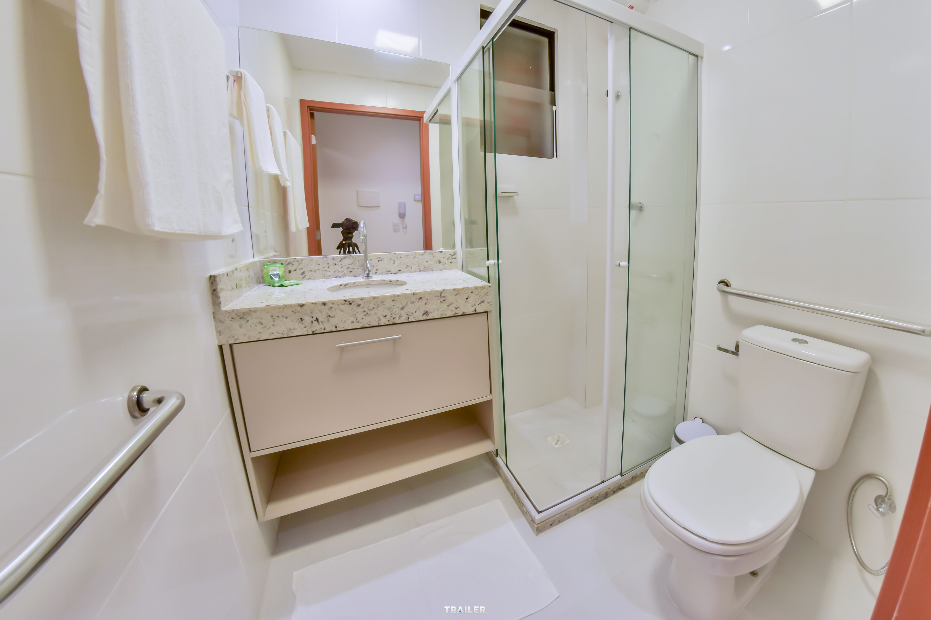 Un baño moderno con cabina de ducha de vidrio, inodoro blanco y lavamanos con encimera de mármol.