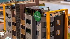 Un edificio moderno de varios pisos con terraza en la azotea, un letrero que dice "Aracaju" y vista al océano.