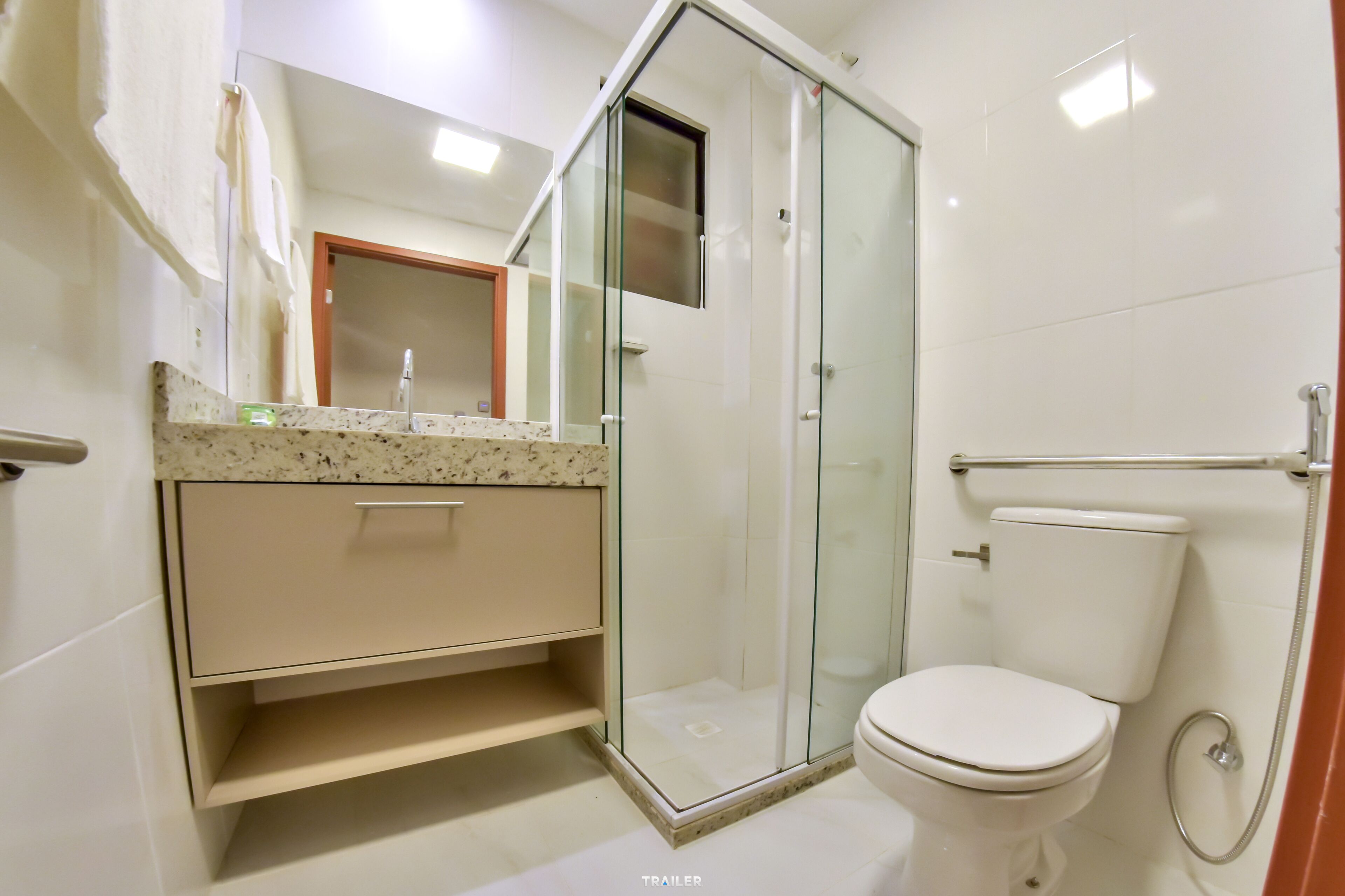 Un baño moderno con ducha de vidrio, inodoro y tocador con lavamanos.