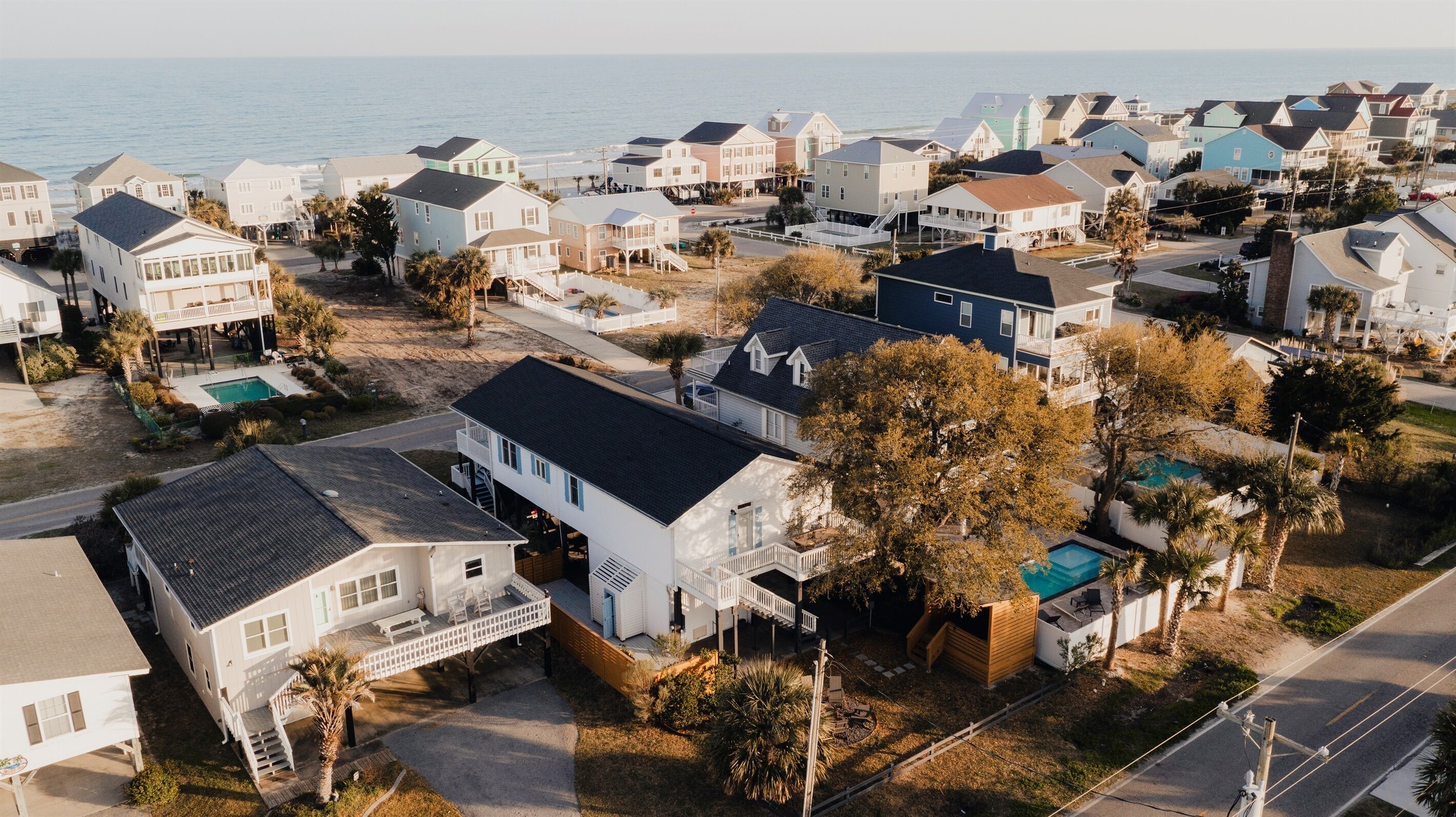 A coastal residential area with houses, a swimming pool, and a view of the ocean.