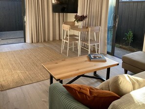 A modern living room with a wooden coffee table, a sofa, and a dining area with a table and chairs.