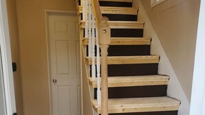 A staircase with wooden steps and white balusters, leading to a door. - (F1) Convenient 3br Syracuse University apartment (Syracuse)