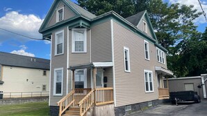 A two-story house with a front porch, a staircase, and a driveway. - (F1) Convenient 3br Syracuse University apartment (Syracuse)