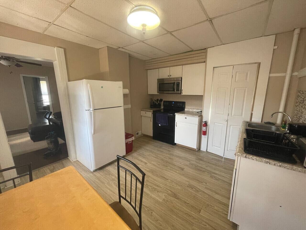 A compact kitchen with a refrigerator, microwave, and stove. There is a dining table with chairs.