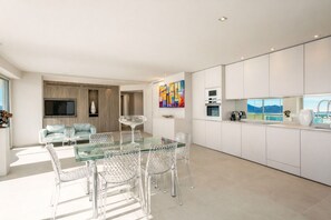 Uma cozinha moderna com armários brancos, uma mesa de jantar de vidro e cadeiras.