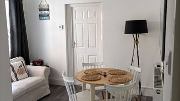 A dining area with a round table, white chairs, and a chandelier.