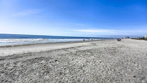 Een breed strand met een heldere lucht en een rustige zee.
