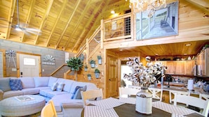 A spacious loft-style living area with a large sofa, dining table, and kitchen area.