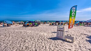 Una playa con sombrillas, sillas y una bandera.