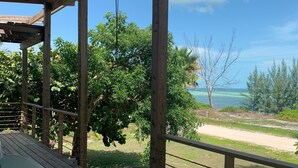 A wooden deck with a view of a beach and ocean. - Ocean view home on canal w/dock in South Bimini (Bimini)