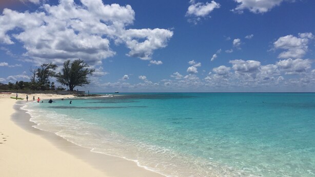 A beach with clear turquoise water, white sand, and a few people in the distance. - Ocean view home on canal w/dock in South Bimini (Bimini)