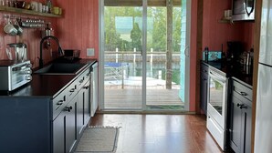 A kitchen with wooden cabinets, a built-in oven, a stainless steel refrigerator, and a large sliding glass door leading to an outdoor deck. - Ocean view home on canal w/dock in South Bimini (Bimini)