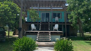 A two-story house with a covered porch, a staircase leading to the upper level, and a pathway in the front yard. - Ocean view home on canal w/dock in South Bimini (Bimini)
