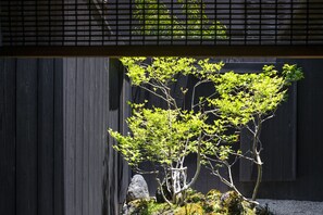 A traditional Japanese garden with a bonsai tree, a rock, and a wooden fence. - Rinn Machiya Kuon (Kyoto)