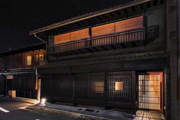A traditional Japanese building with a wooden exterior, a tiled roof, and a balcony with railings.