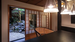 A traditional Japanese room with tatami flooring, a low table, and a shoji screen door leading to a garden. - Rinn Machiya Kuon (Kyoto)
